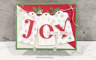 A red, white, and green Christmas card with the word "JOY" on the front