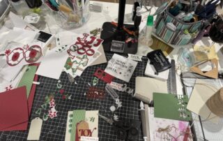 A messy desk covered in card-making supplies