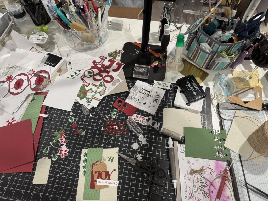 A messy desk covered in card-making supplies